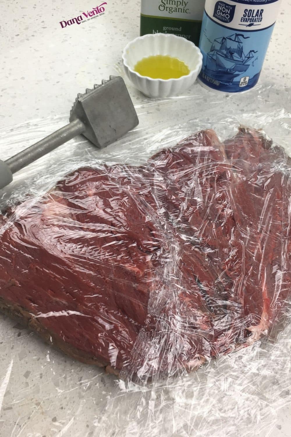 beef tenderloin between plastic wrap and mallet