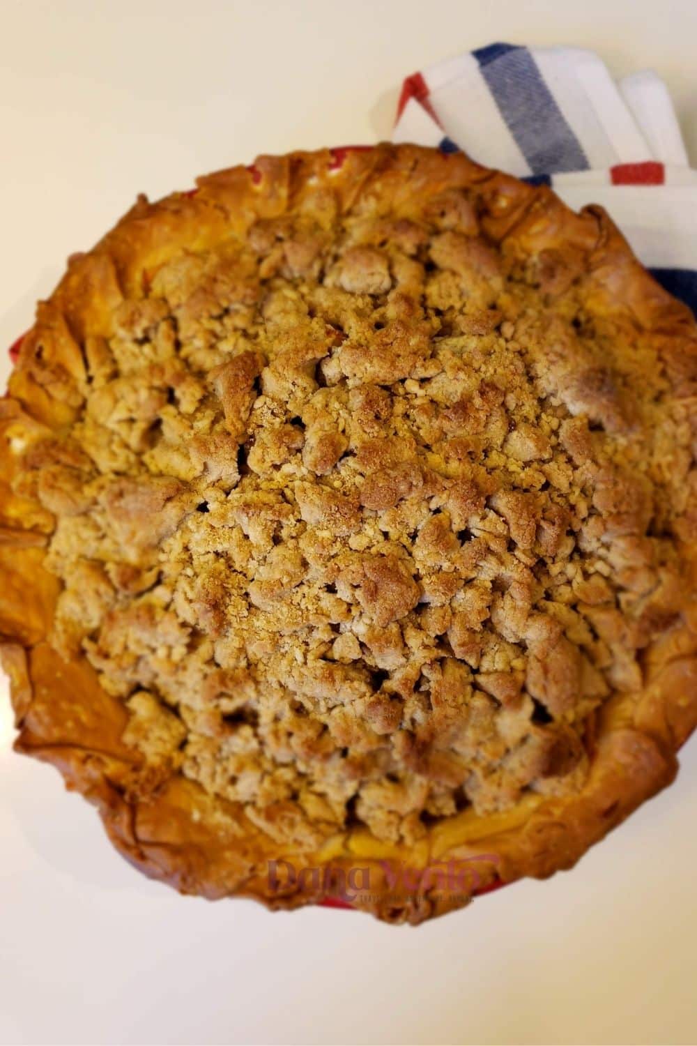 The reveal of a baked Peach crumble pie from above after coming out of the oven to cool