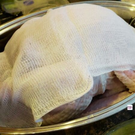 Turkey in a cheesecloth with 3 ingredient turkey basting sauce covered