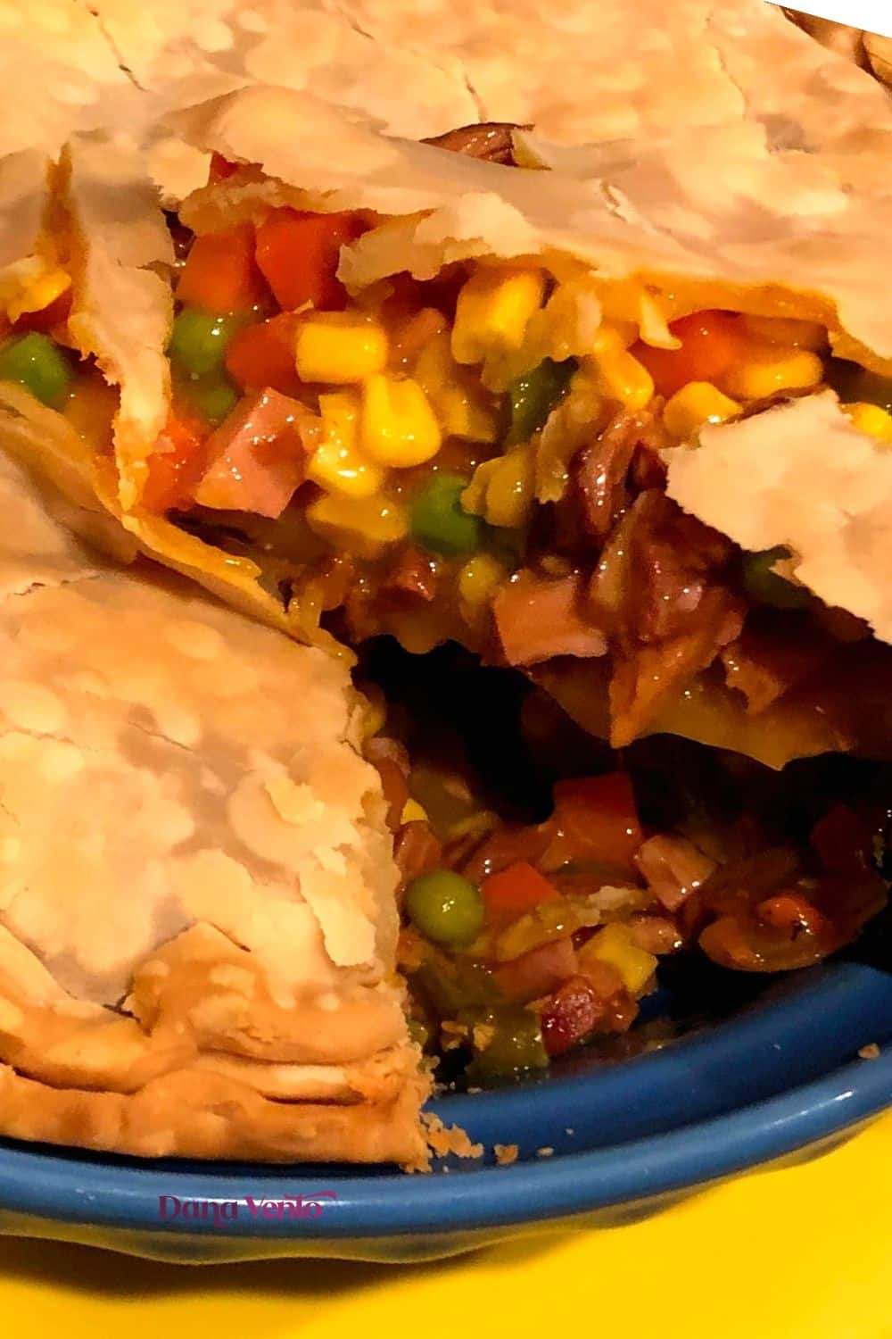 flaky buttery crust with ham and veggies showing in meat pie