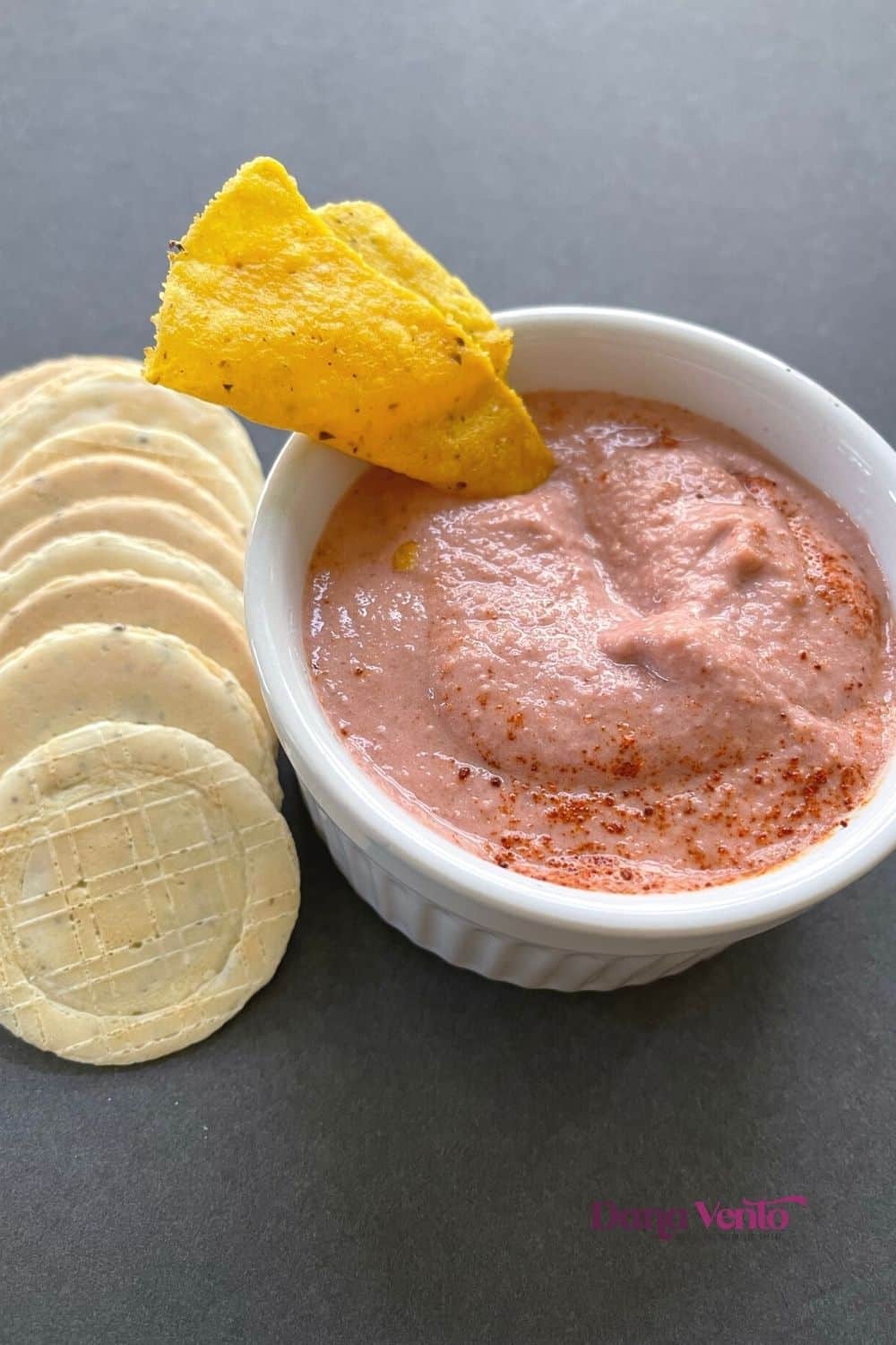 pink hummus in a bowl with crackers and tortilla chip