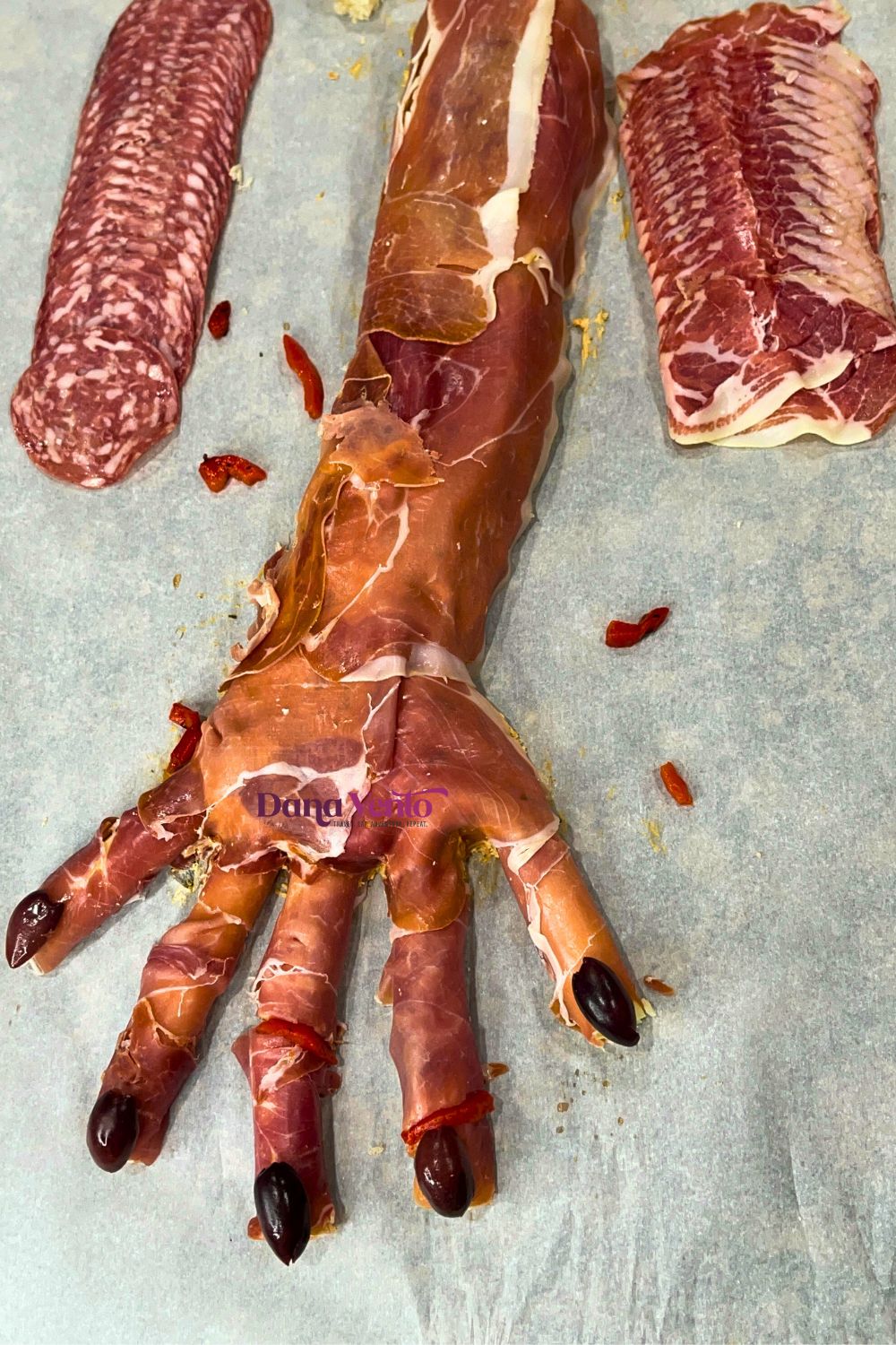 Edible amputated hand appetizer for Halloween with Kalamata nails and cuts of roasted red peppers for blood (Pinterest Carousel Ad)