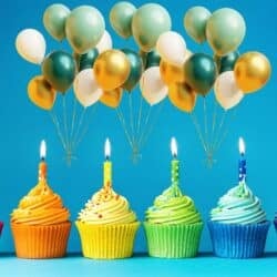 Birthday party planning cupcakes with colorful frosting, lit candles, and gold, white, and teal balloons against a bright blue background