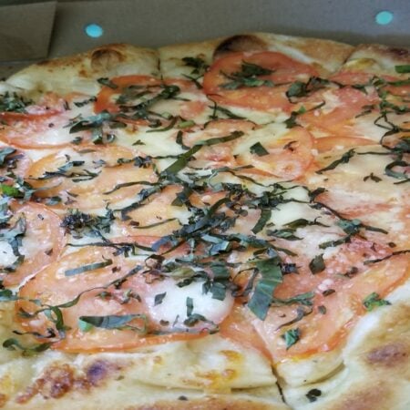 Freshly baked Margherita pizza with basil and mozzarella in a restaurant-style setting