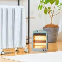 A tall white radiator-style heater and a small glowing portable heater side by side in a modern living room.