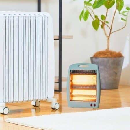 A tall white radiator-style heater and a small glowing portable heater side by side in a modern living room.