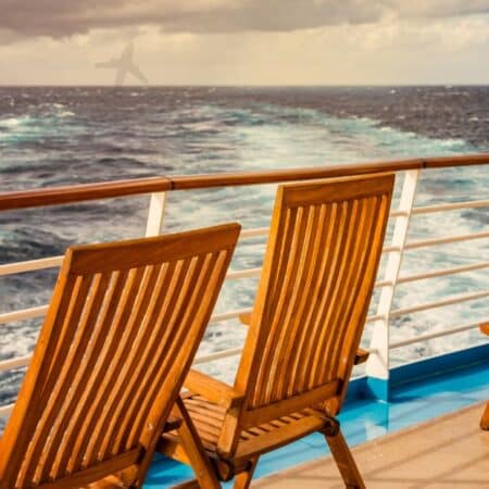 View from a cruise ship balcony with wooden deck chairs overlooking the deep blue Mediterranean Sea at sunset — the essence of luxury Mediterranean cruises
