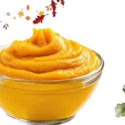 Creamy pumpkin puree in a glass bowl with autumn leaves and watercolor pumpkins – festive Thanksgiving kitchen concept.
