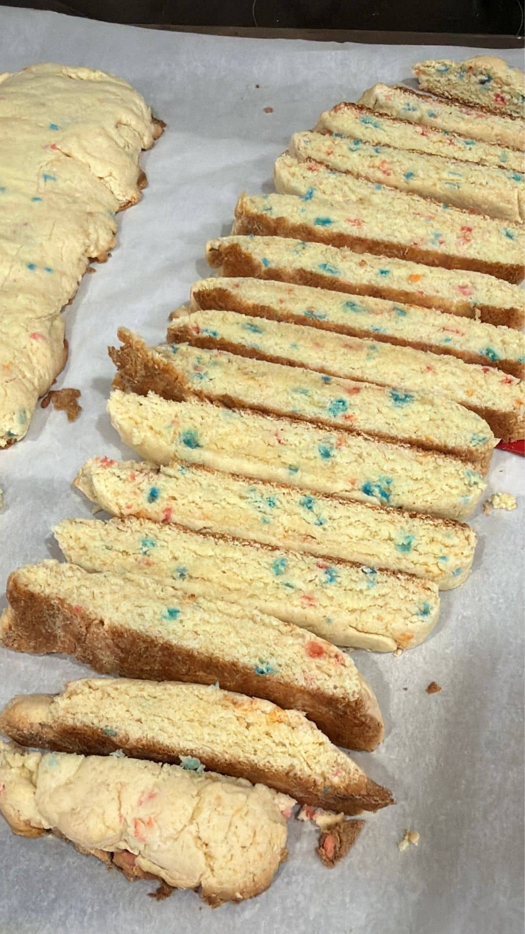  Funfetti biscotti sliced and baked with colorful sprinkles on parchment paper