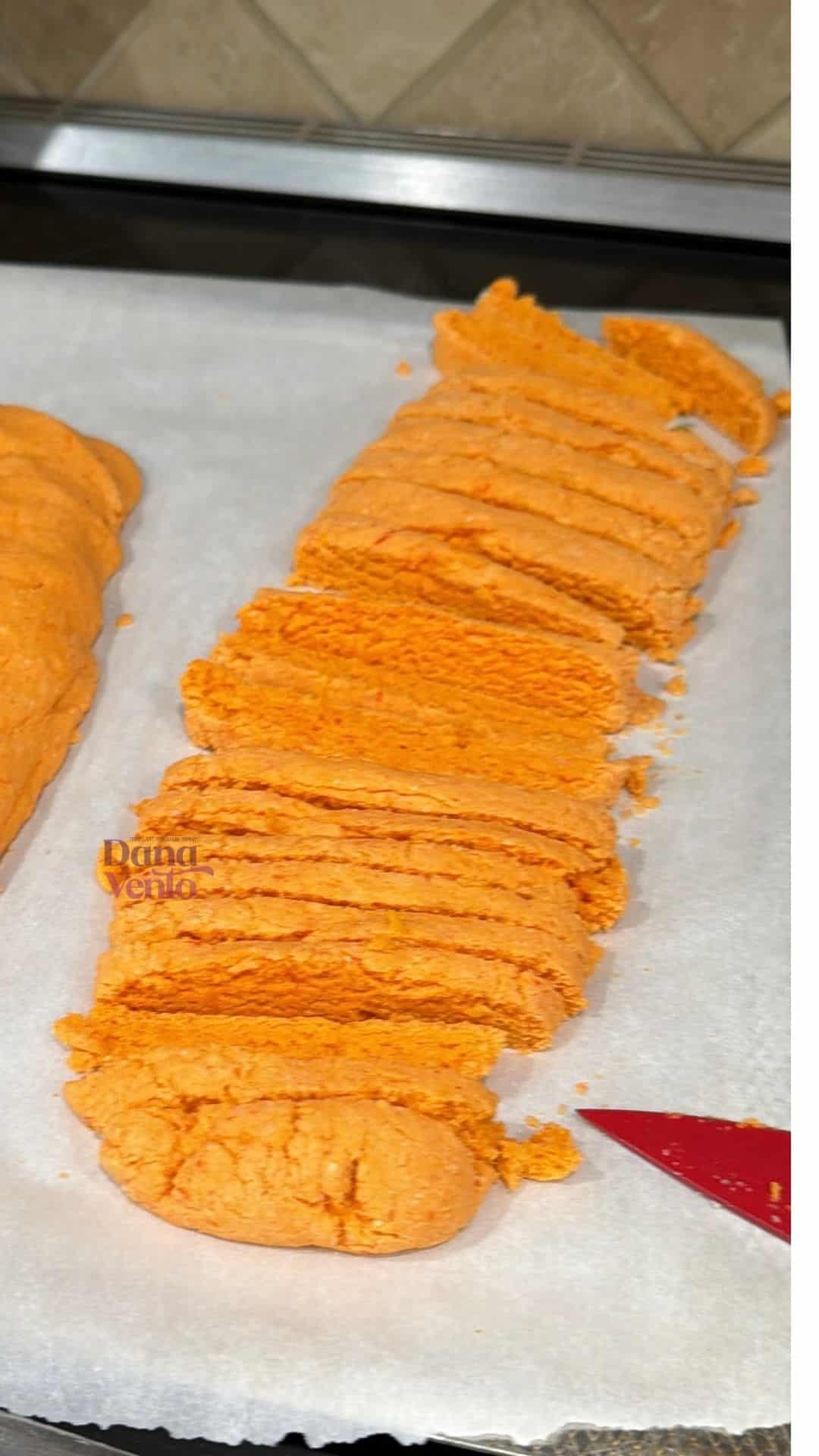  Orange biscotti loaf sliced into pieces on parchment paper showing bright citrus color